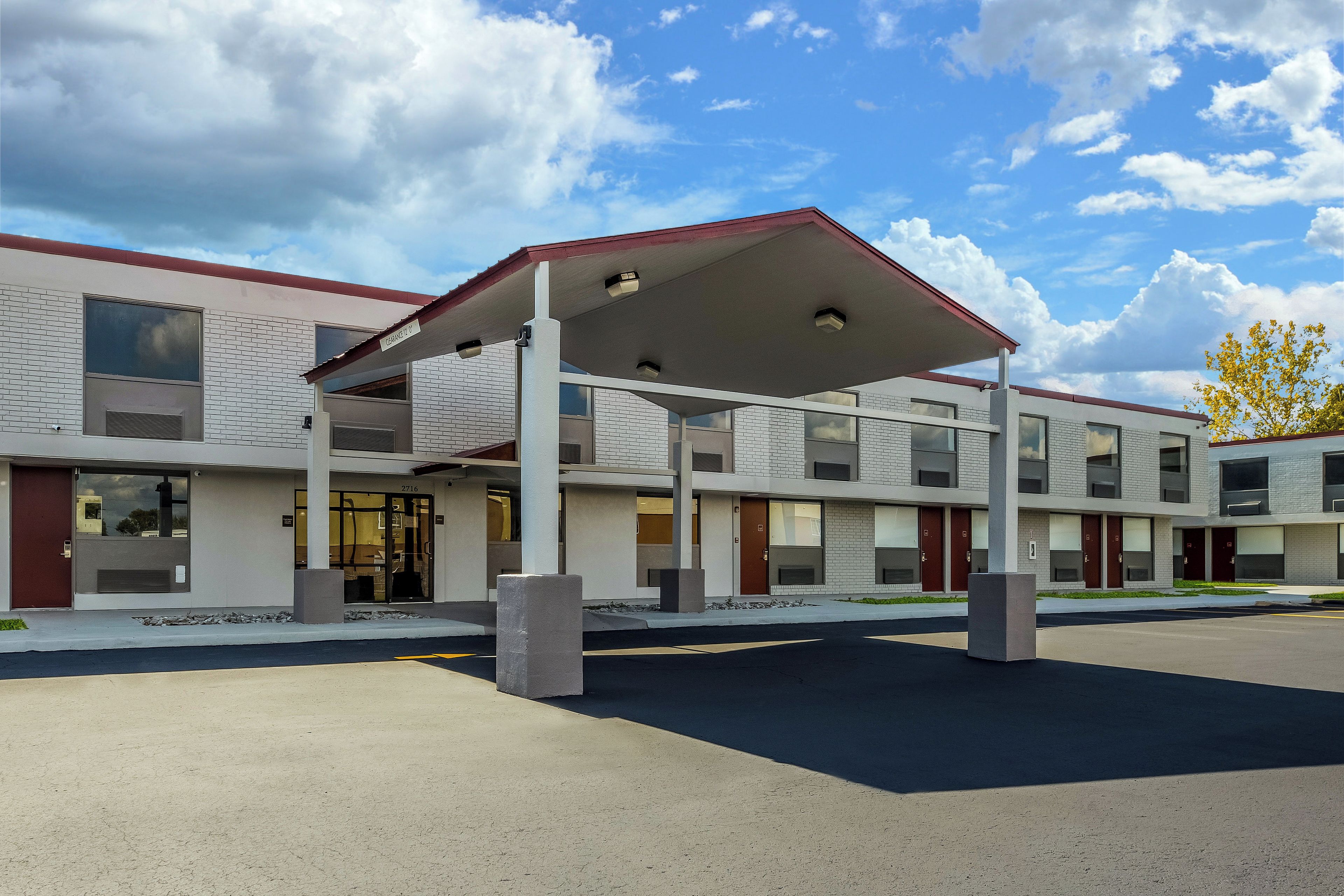 A modern building with a covered entrance, multiple windows, and a parking area.
