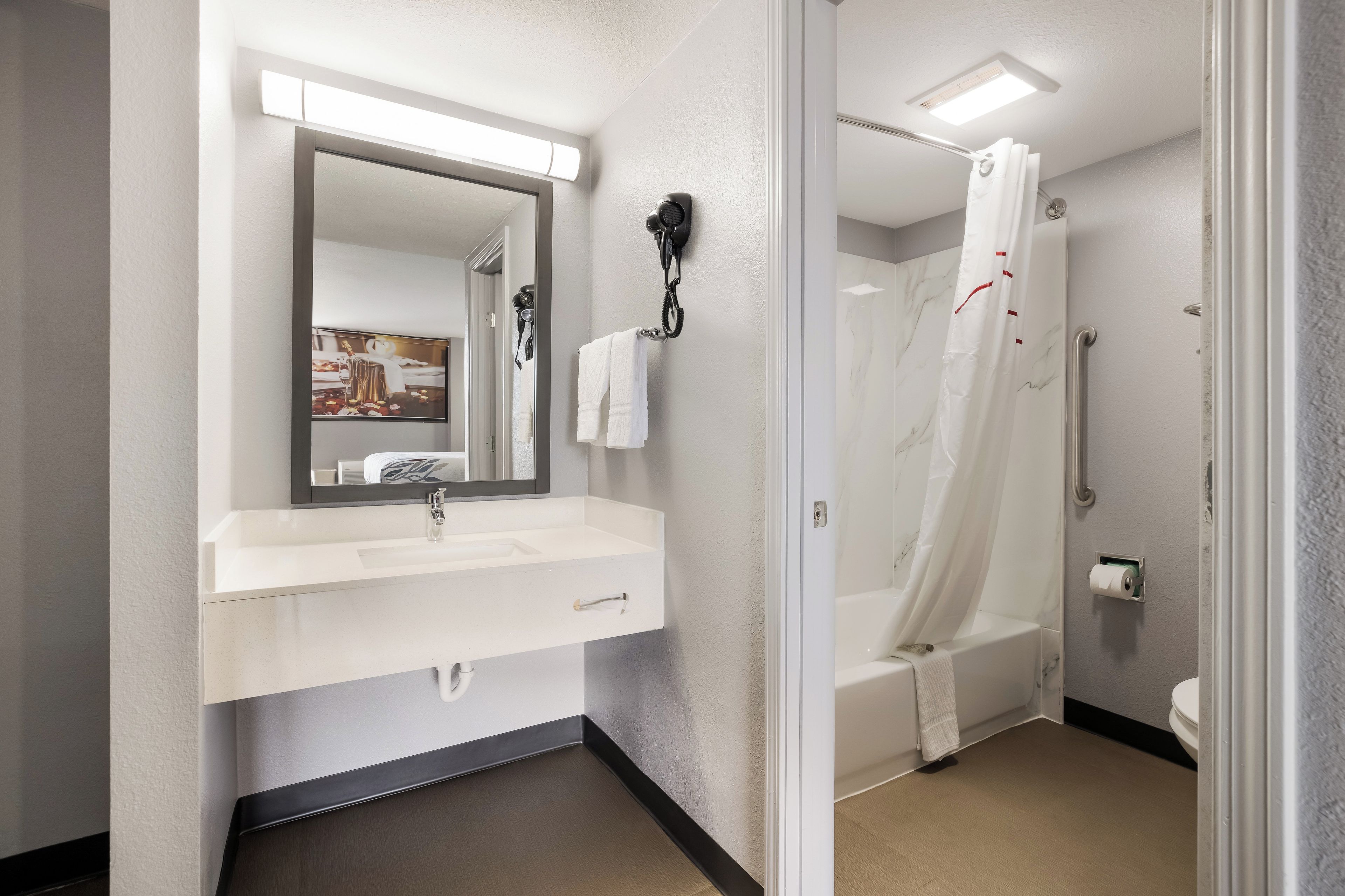 A modern bathroom with a white sink, mirror, and shower curtain.