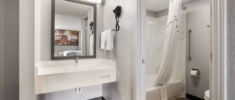 Un baño moderno con un lavabo blanco, espejo y cortina de ducha.