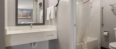 A bathroom with a sink, mirror, hair dryer, shower, and toilet.