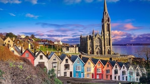 A historic church with a tall spire and colorful houses in the foreground. - Leonardo Hotel Cork (Cork)