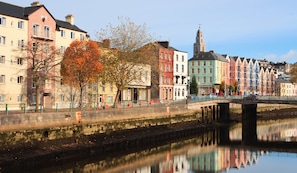 A riverside view with a bridge, colorful buildings, and autumn trees.