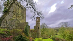 A historic castle with a prominent tower, surrounded by lush greenery and a well-maintained garden. - Leonardo Hotel Cork (Cork)
