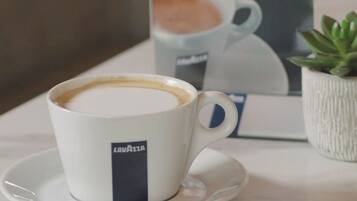 A cup of Lavazza coffee on a saucer with a sign in the background advertising the coffee.
