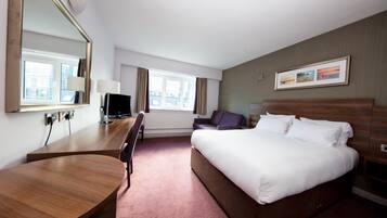 Une chambre d’hôtel avec un lit, un bureau, une chaise, une télévision et une fenêtre.