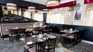 A restaurant interior with multiple dining tables, chairs, and hanging pendant lights. - Leonardo Hotel Cork (Cork)