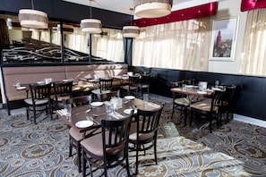 A restaurant interior with multiple dining tables, chairs, and hanging pendant lights. - Leonardo Hotel Cork (Cork)