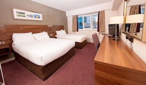 A hotel room with two beds, a desk, a TV, and a window with curtains. - Leonardo Hotel Cork (Cork)