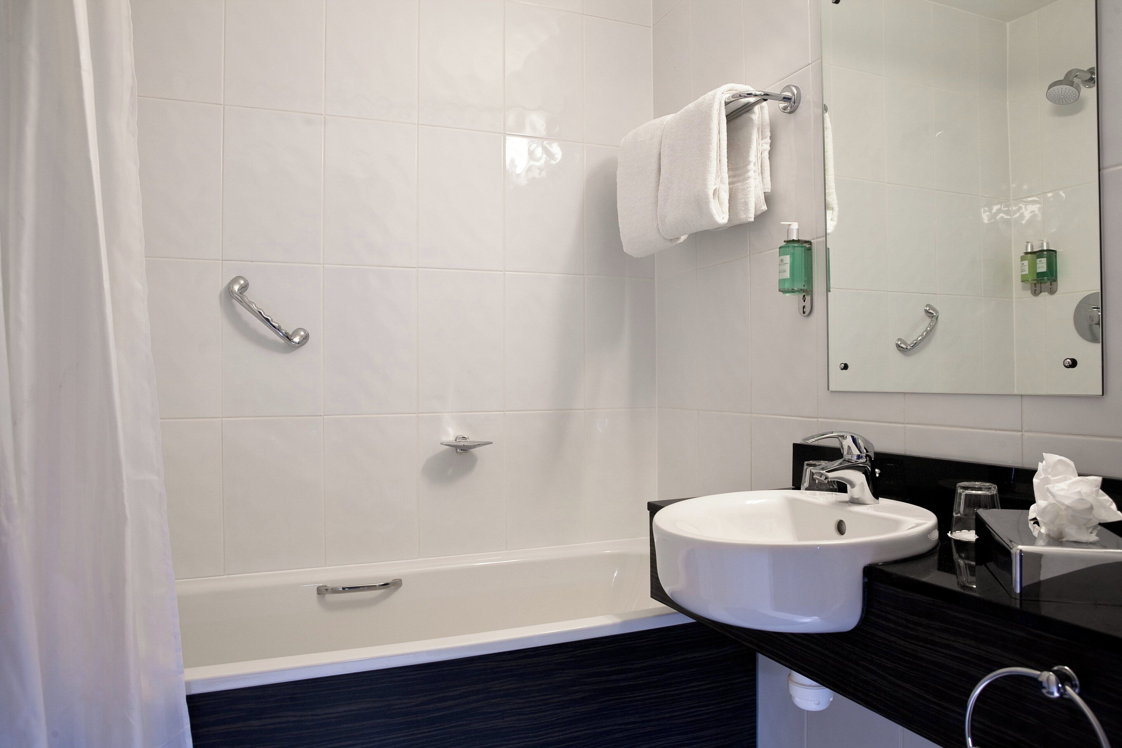 A modern bathroom with a bathtub, a sink, and a mirror.
