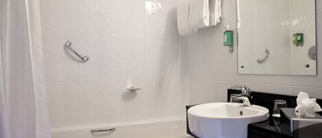 Un baño moderno con bañera, lavamanos y espejo.