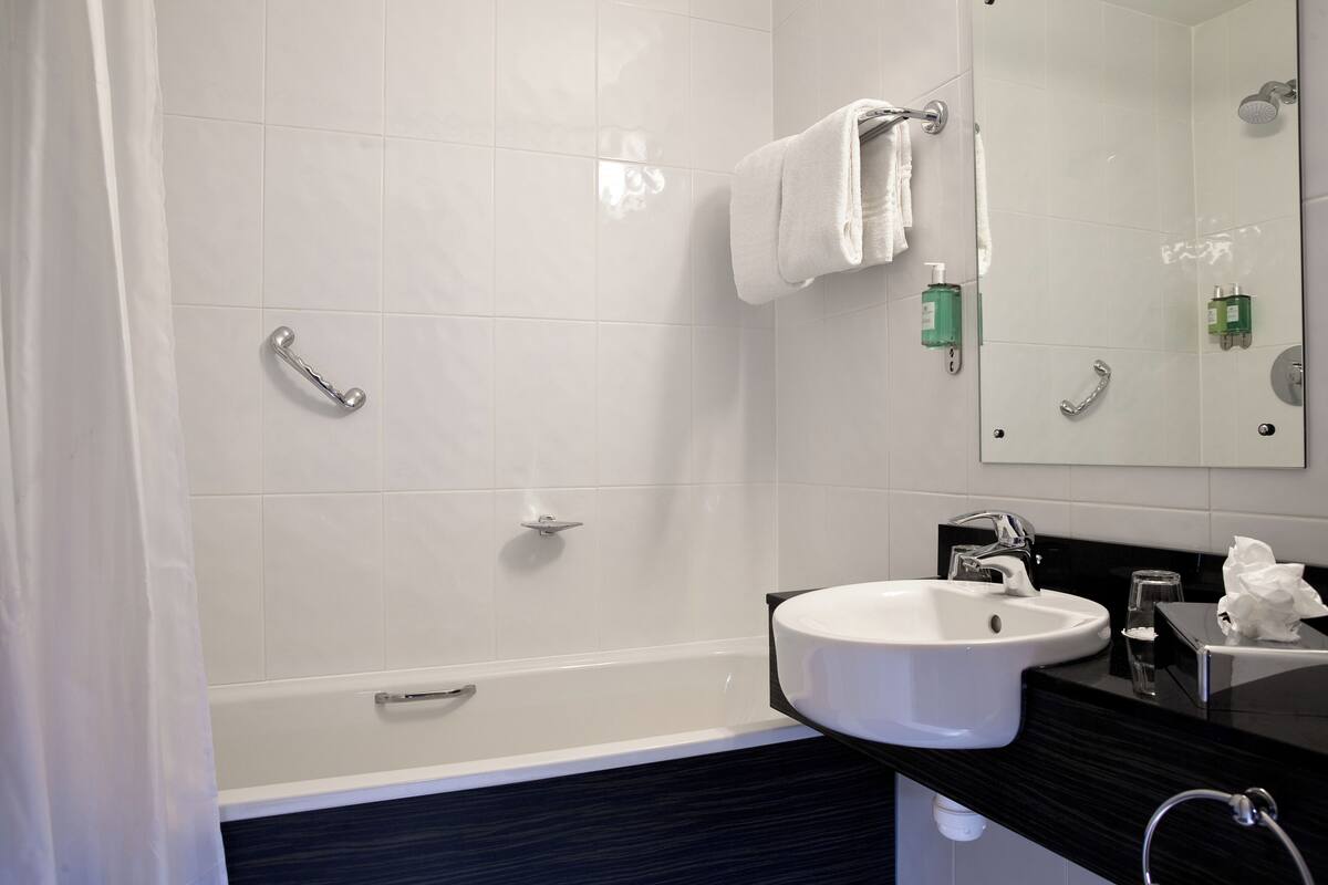 Un baño moderno con bañera, lavamanos y espejo.