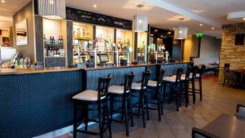 A bar area with multiple seating options and a variety of liquor bottles.