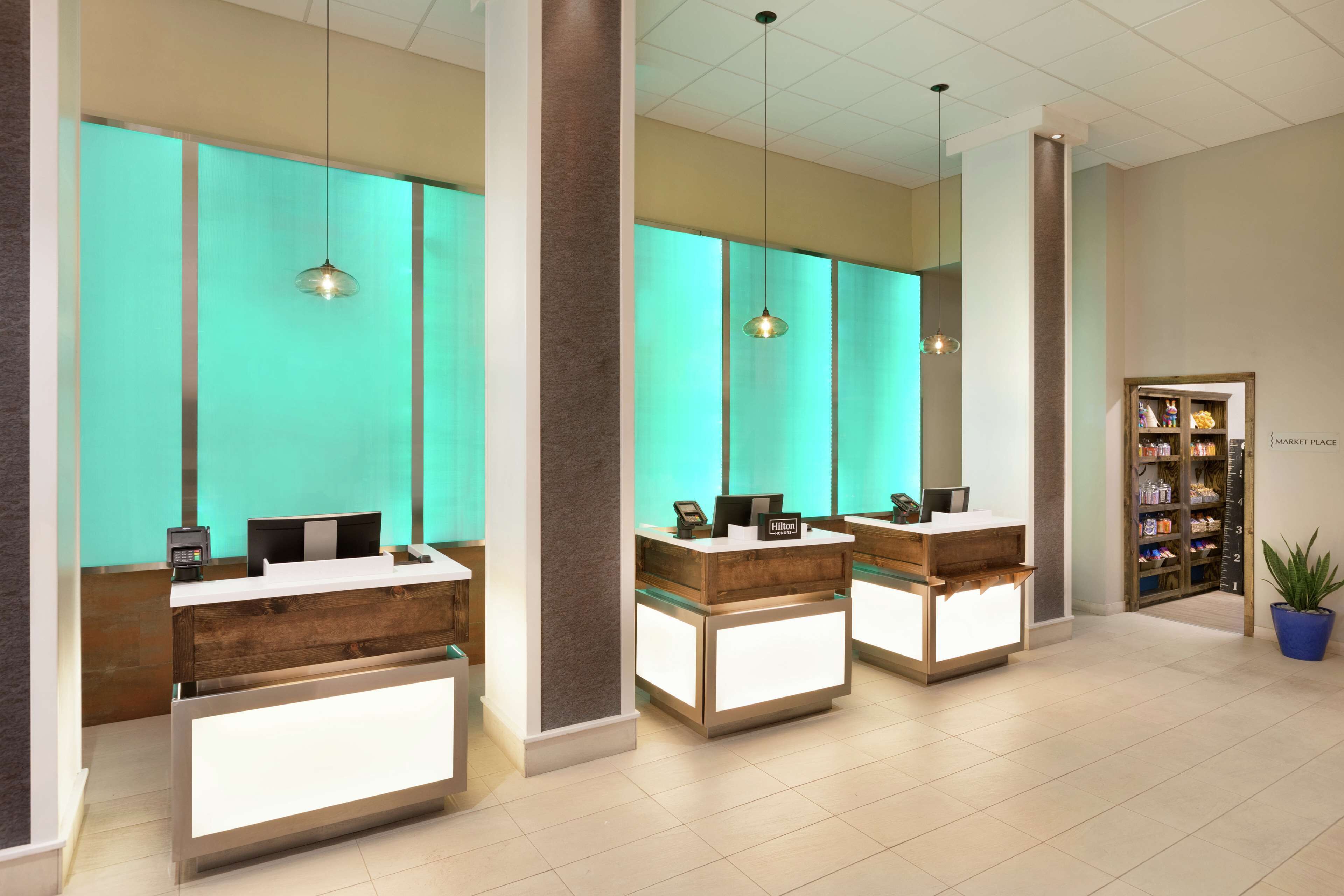 Een hotel receptie met drie balies, een schaalmodel en een plant.