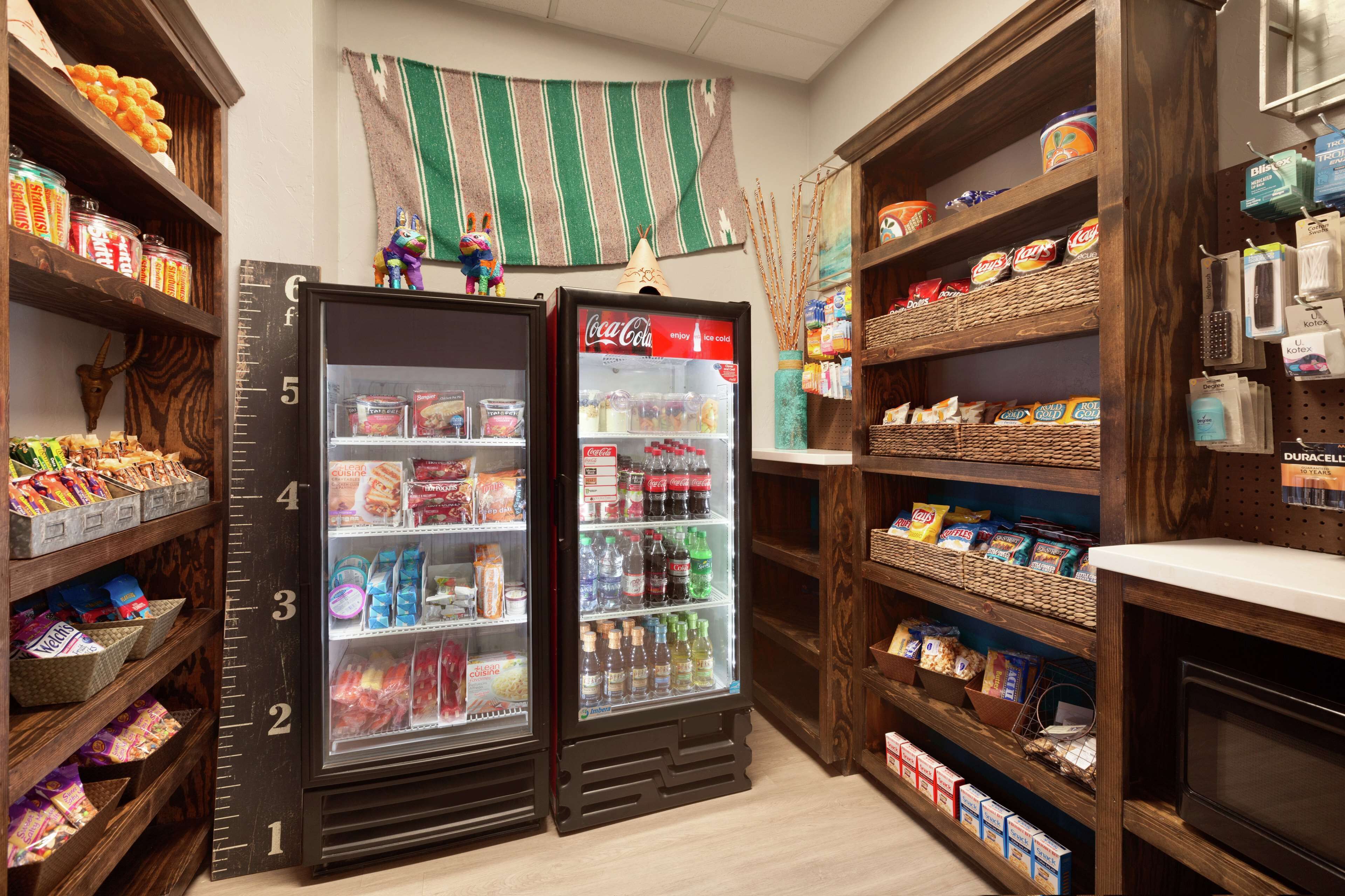 A snack and beverage kiosk with shelves stocked with snacks, drinks, and a Coca-Cola refrigerator.