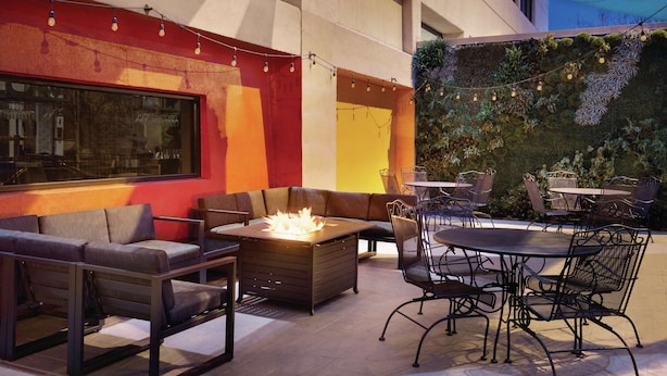 Un espace extérieur aménagé avec un foyer, des sièges confortables et des tables avec des chaises.