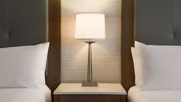 Un lit bien fait, avec un oreiller blanc et une table de chevet sur laquelle se trouve une lampe.