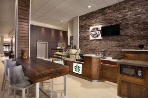 A coffee shop interior with a wooden counter, a Starbucks logo, and a brick wall.