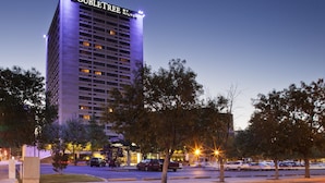 Un grand hôtel, avec un panneau bien visible indiquant « DOUBLETREE BY HILTON », entouré d’arbres et de voitures garées.