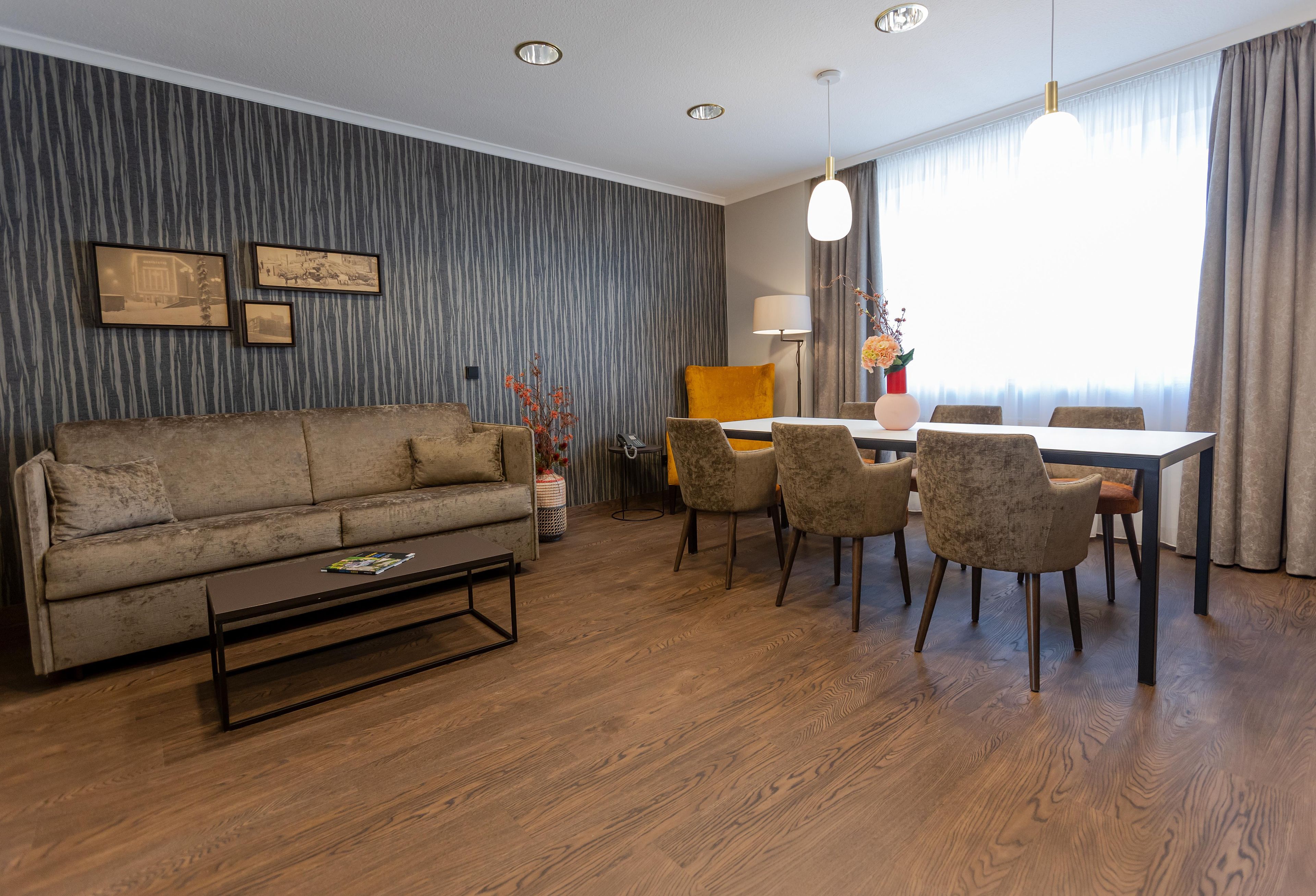 Ein Wohnzimmer mit einer Couch, einem Couchtisch und einem Essbereich mit Stühlen und einem Tisch.
