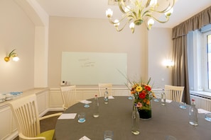 Un salón de conferencias con una mesa redonda, sillas, una pizarra y un centro de mesa floral.