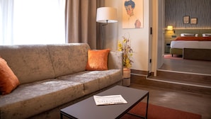 A hotel room with a sofa, a coffee table, a lamp, and a bed.