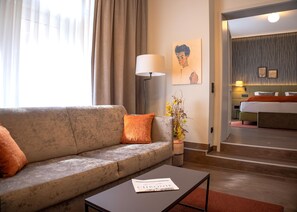 Une chambre d’hôtel avec un canapé, une table basse, une lampe et un lit.