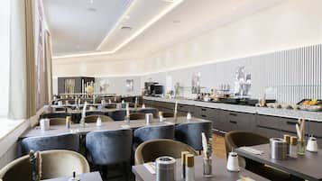 Ein modernes Restaurant mit mehreren Tischen und Stühlen, einer Küchenzeile und einer Wand mit Muster.