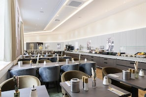 Un restaurante moderno con varias mesas y sillas, una zona de cocina y una pared con diseño.