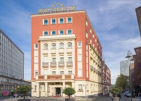 Un hotel con fachada roja y color crema, múltiples ventanas y un letrero que indica que es el Hotel Essener Hof.