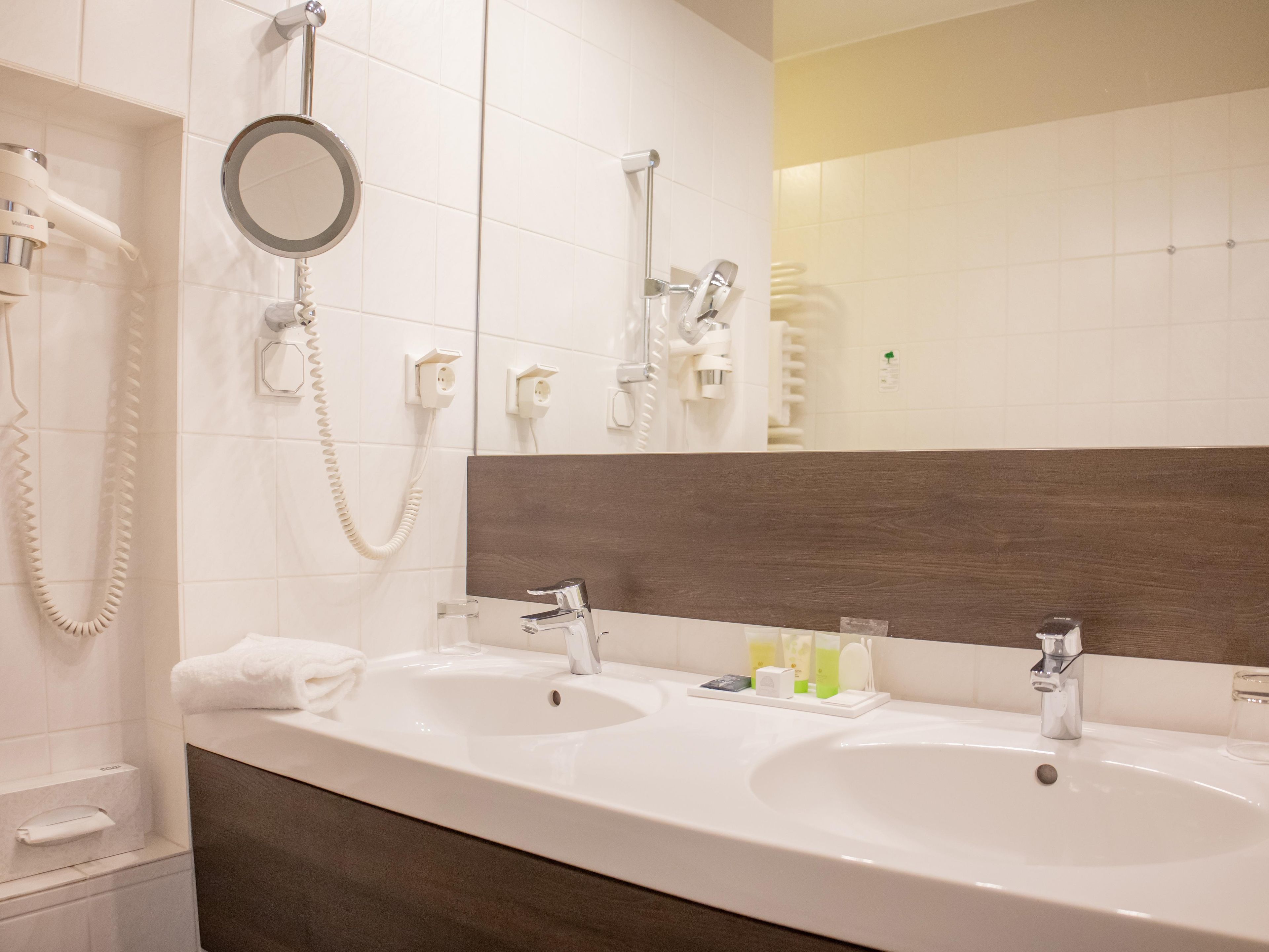 Un baño de hotel con dos lavamanos, un espejo y una ducha.