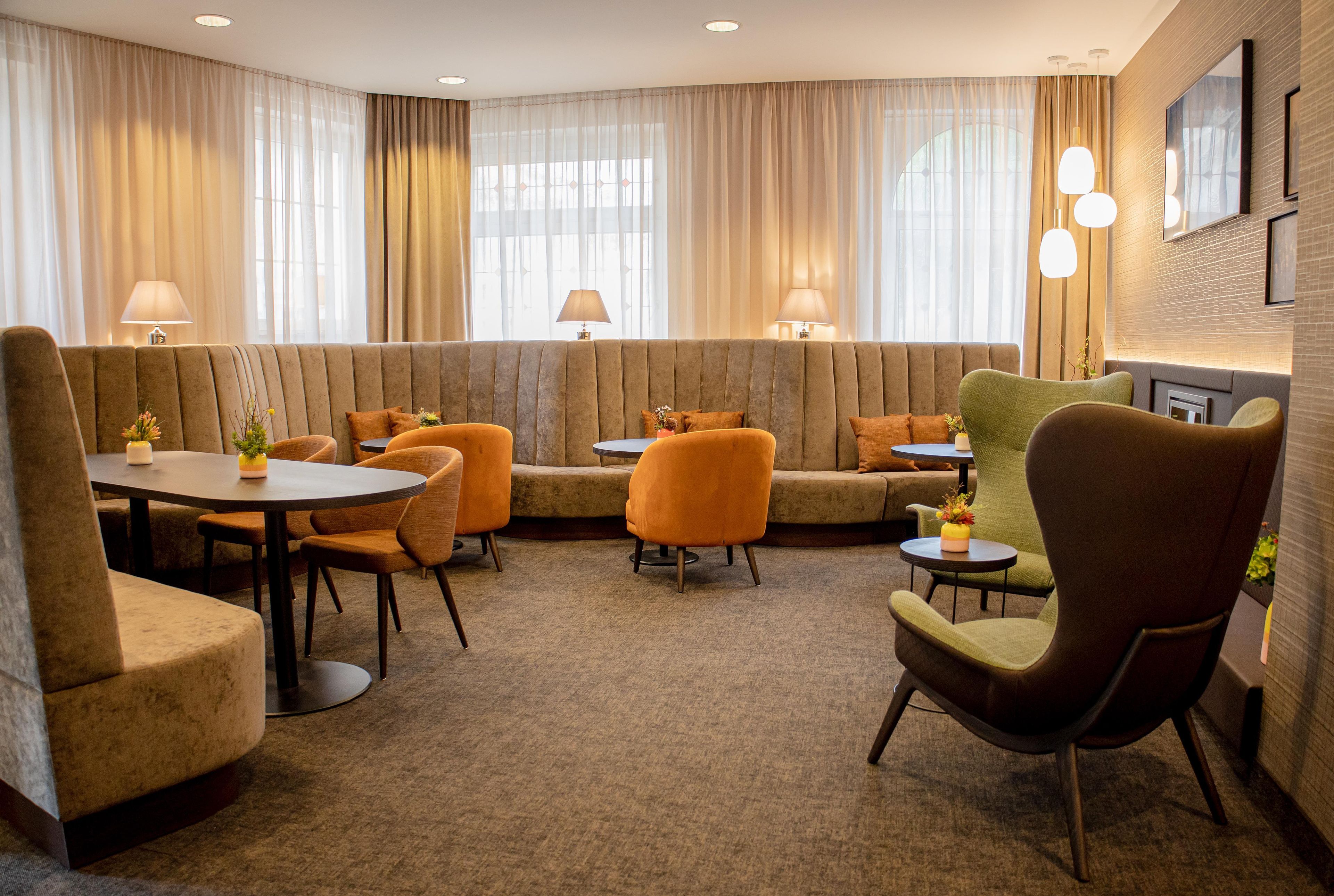 Ein Hotelzimmer mit Sitzecke, ausgestattet mit Sofas und Sesseln, einem kleinen Tisch und einer Lampe.