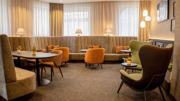 Ein Hotelzimmer mit Sitzecke, ausgestattet mit Sofas und Sesseln, einem kleinen Tisch und einer Lampe.