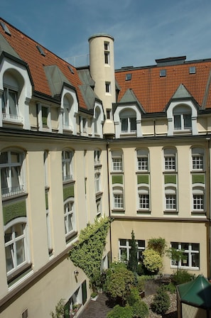 Un immeuble à plusieurs étages doté d’une cour intérieure, présentant un mélange de styles architecturaux, avec des fenêtres en arc et une structure en forme de tour.
