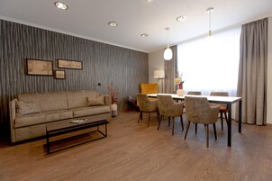 Una sala de estar moderna con sofá, mesa de centro, mesa de comedor, sillas y una lámpara.