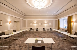 Un salón de conferencias con una mesa larga, sillas y un candelabro.