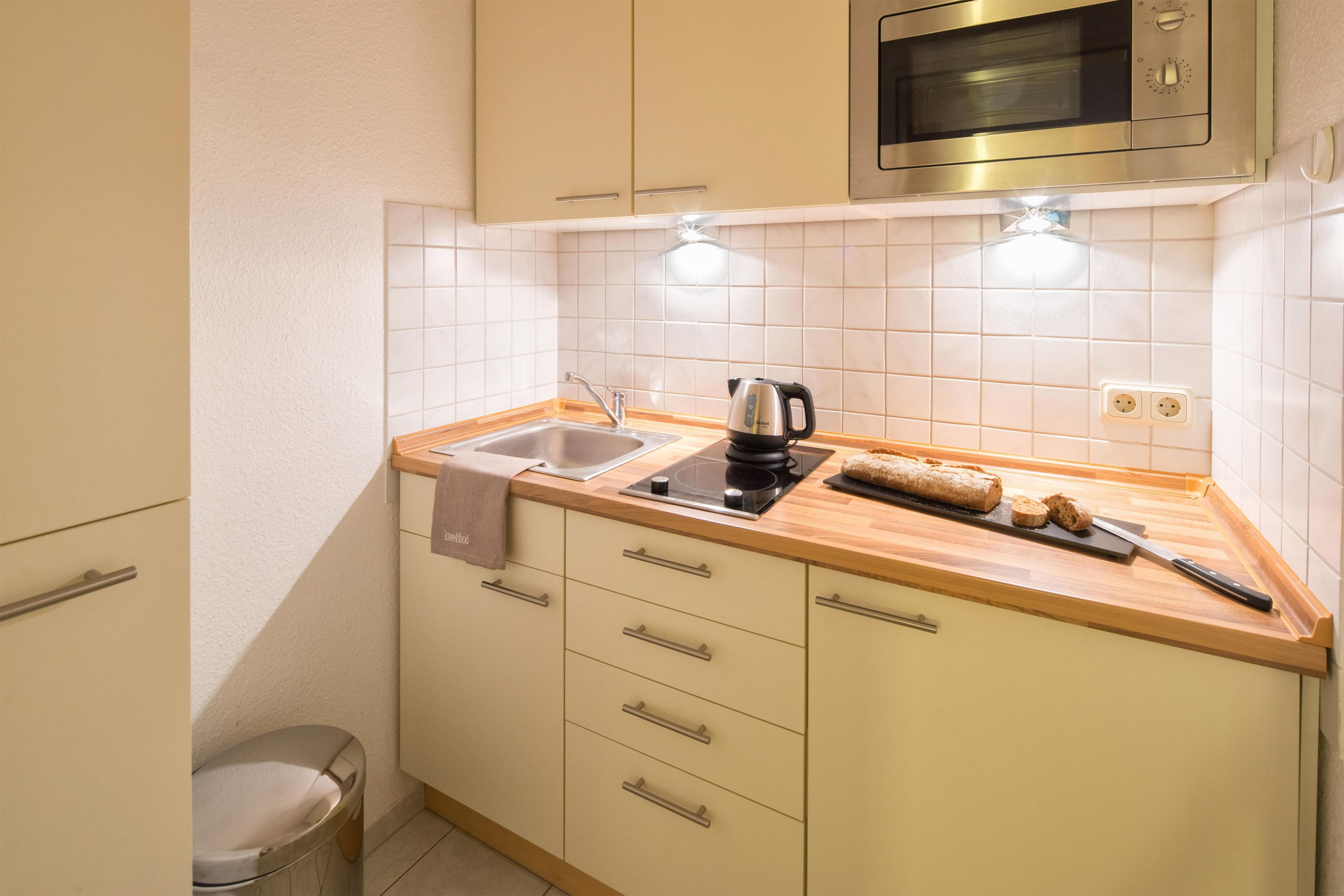 Eine kompakte Küche mit Spüle, Wasserkocher, Toaster und einem Brot auf der Arbeitsfläche.