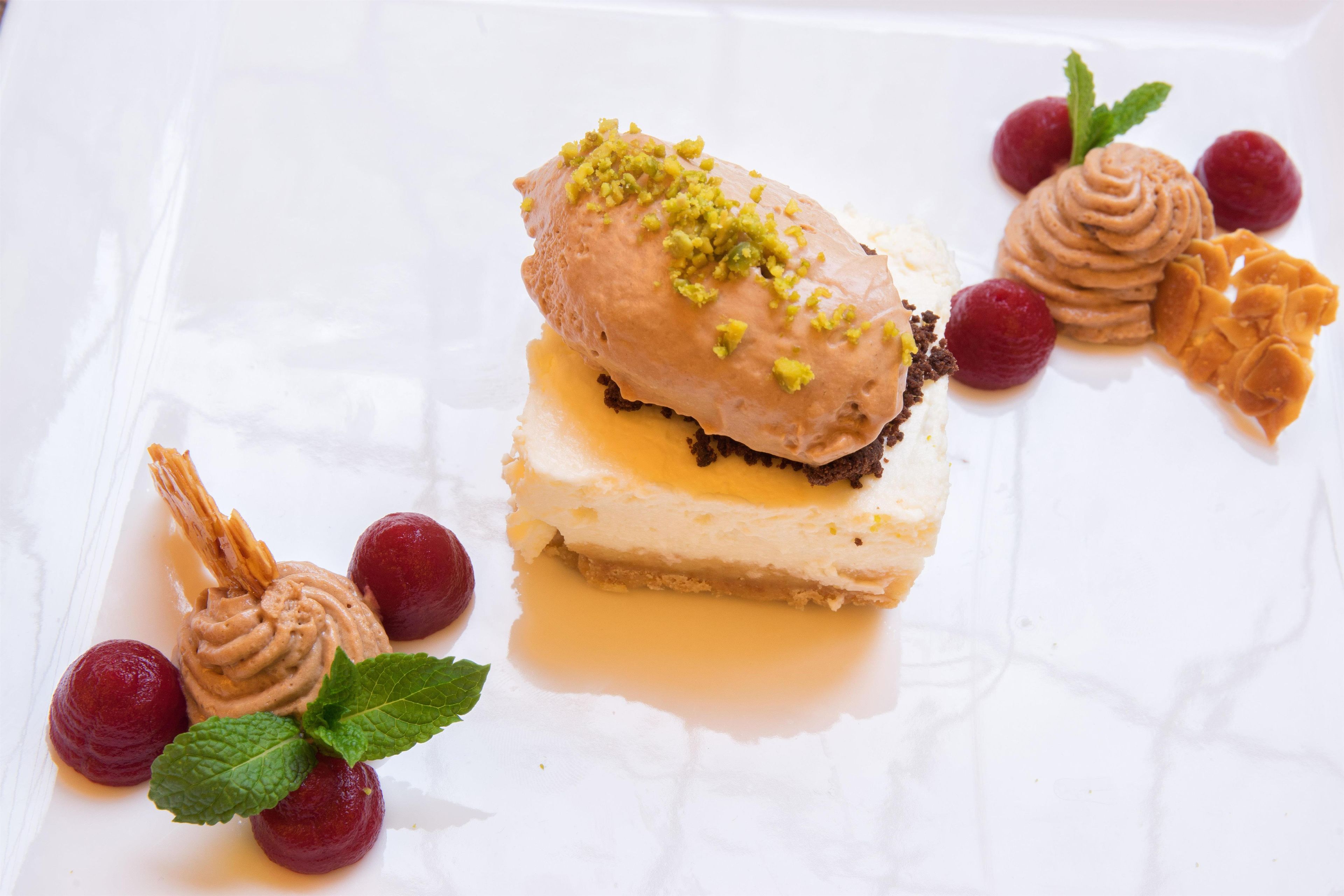 A dessert plate with a layered cake, raspberries, and mint leaves.