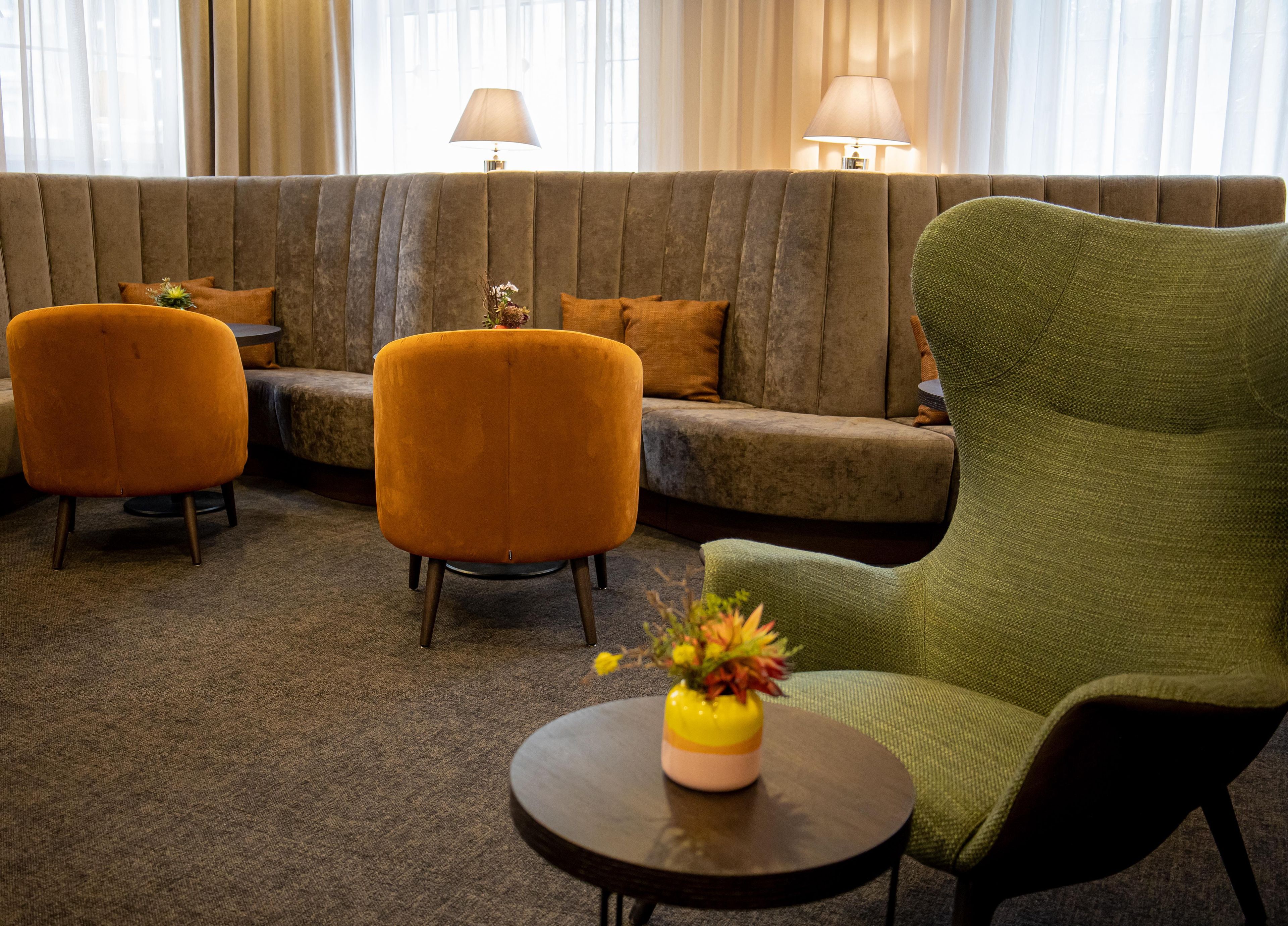 A seating area with a sofa, two armchairs, and a small table with a vase.