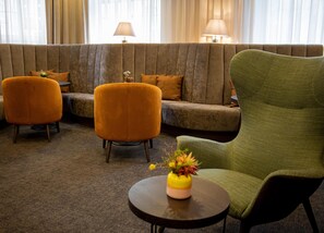 Un coin salon comprenant un canapé, deux fauteuils et une petite table sur laquelle est posé un vase.