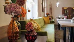Une pièce avec un canapé vert, une table à manger et un vase rempli de fleurs posé sur une table.