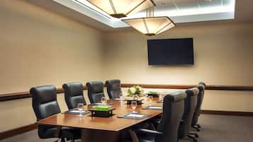 Una sala de conferencias con una mesa grande, seis sillas, un televisor de pantalla plana y una lámpara en el techo.