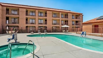 A hotel with a swimming pool, outdoor seating, and a multi-story building with balconies.