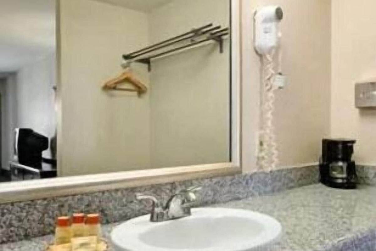A bathroom with a sink, mirror, towel rack, and a hairdryer on the wall.