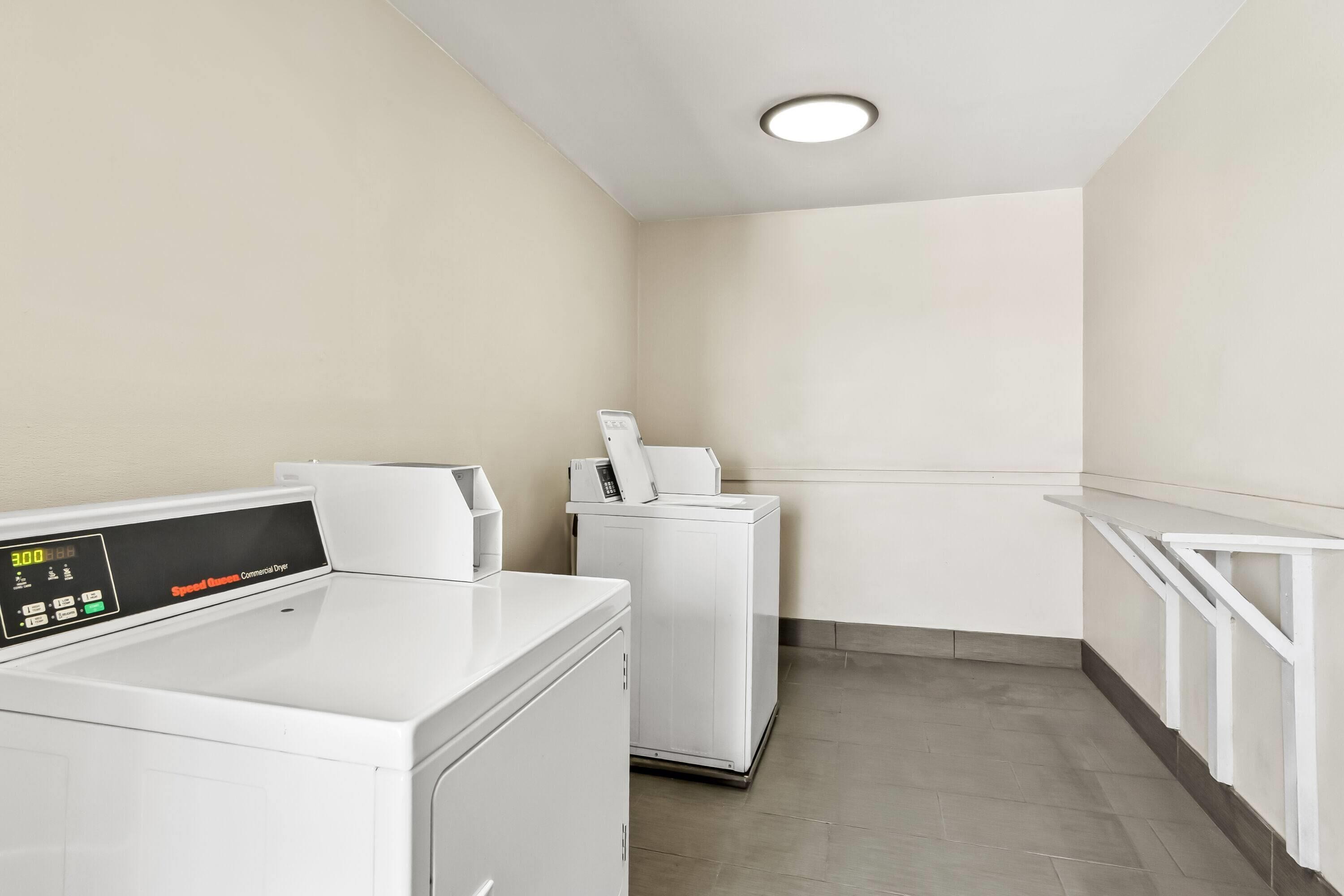 A laundry area with two white washing machines and a control panel.