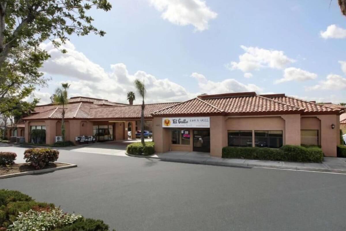A building with a sign that reads 'El Gallo Bar & Grill' and a parking lot in front.