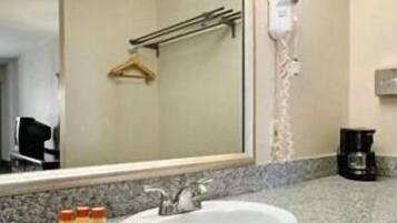 A bathroom with a sink, mirror, towel rack, and a hairdryer on the wall.