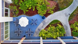 An outdoor patio with tables and chairs, surrounded by greenery and a curved pathway. - Quality Inn Orlando Near International Drive (Orlando)