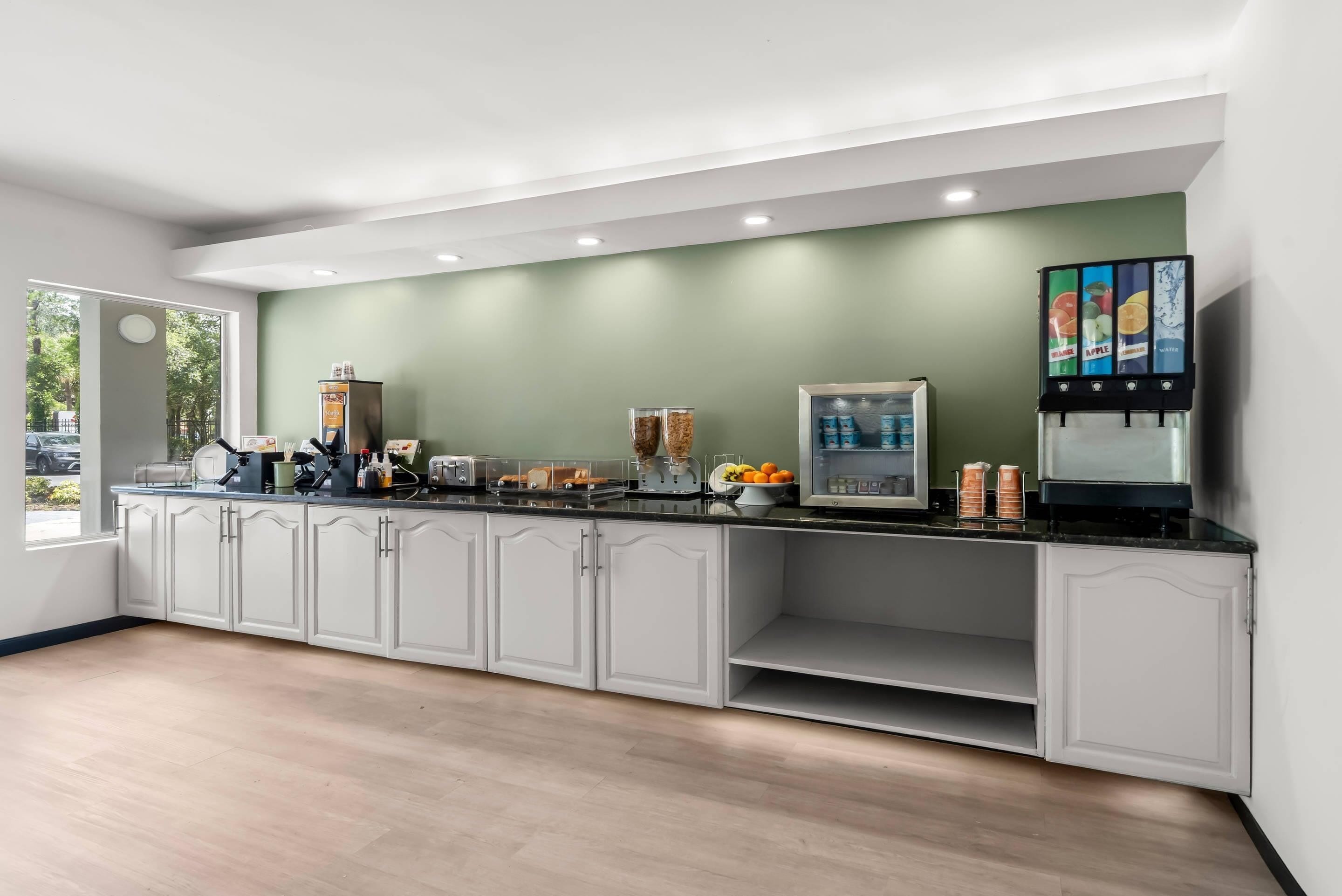 A modern kitchen with a black countertop, white cabinetry, and a green accent wall.