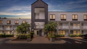 A modern hotel with a central tower, multiple balconies, and a parking area. - Quality Inn Orlando Near International Drive (Orlando)