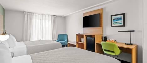 A hotel room with two beds, a desk with a computer, a TV, and a chair.